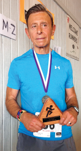 Rich D’Accurzio displays the first-place medal he won in the over-50 age group at the Delta Lake Half-Marathon.