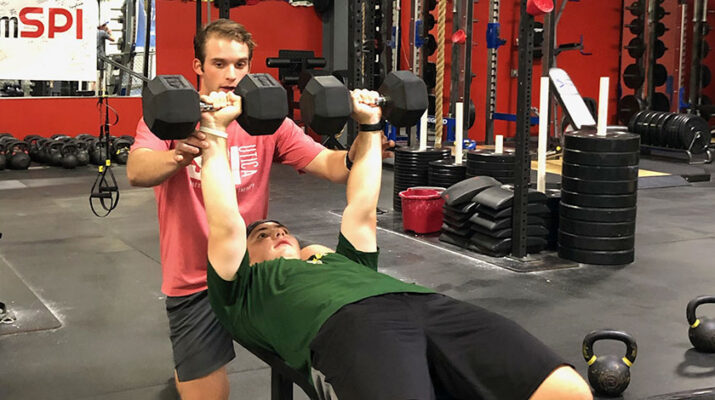 SPI Strength and Conditioning Coach Jared Smaldon (in red T-shirt) trains student athletes at the fitness center, preparing them for the fall sports season.